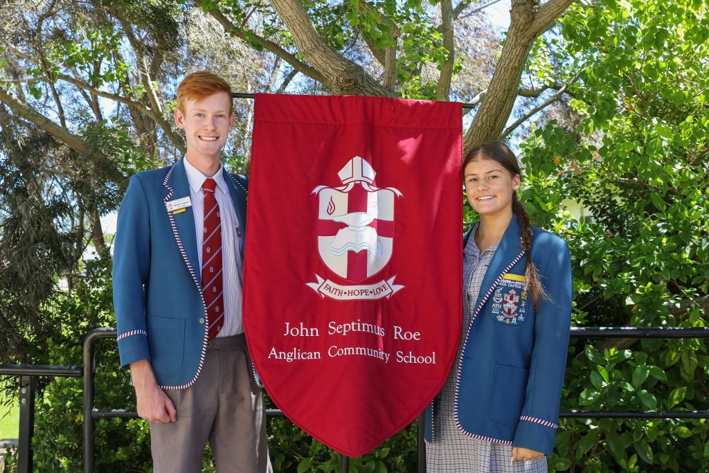 Pictured are to JSRACS students holding our school banner. They stand either side of it smiling