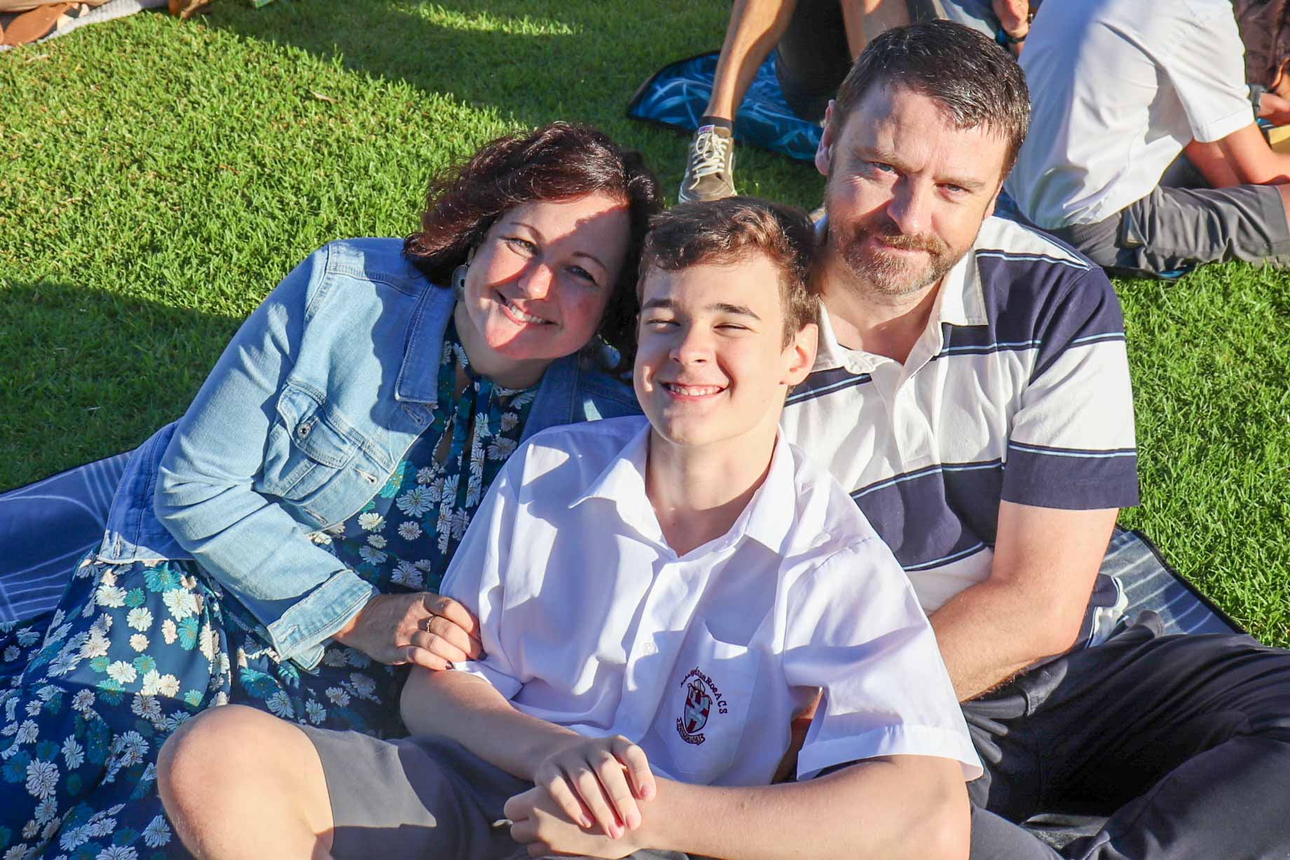 Pictured is a mother, father and son at The Rite Journey Call and Departure Ceremony. They huddle up and smile at the camera.