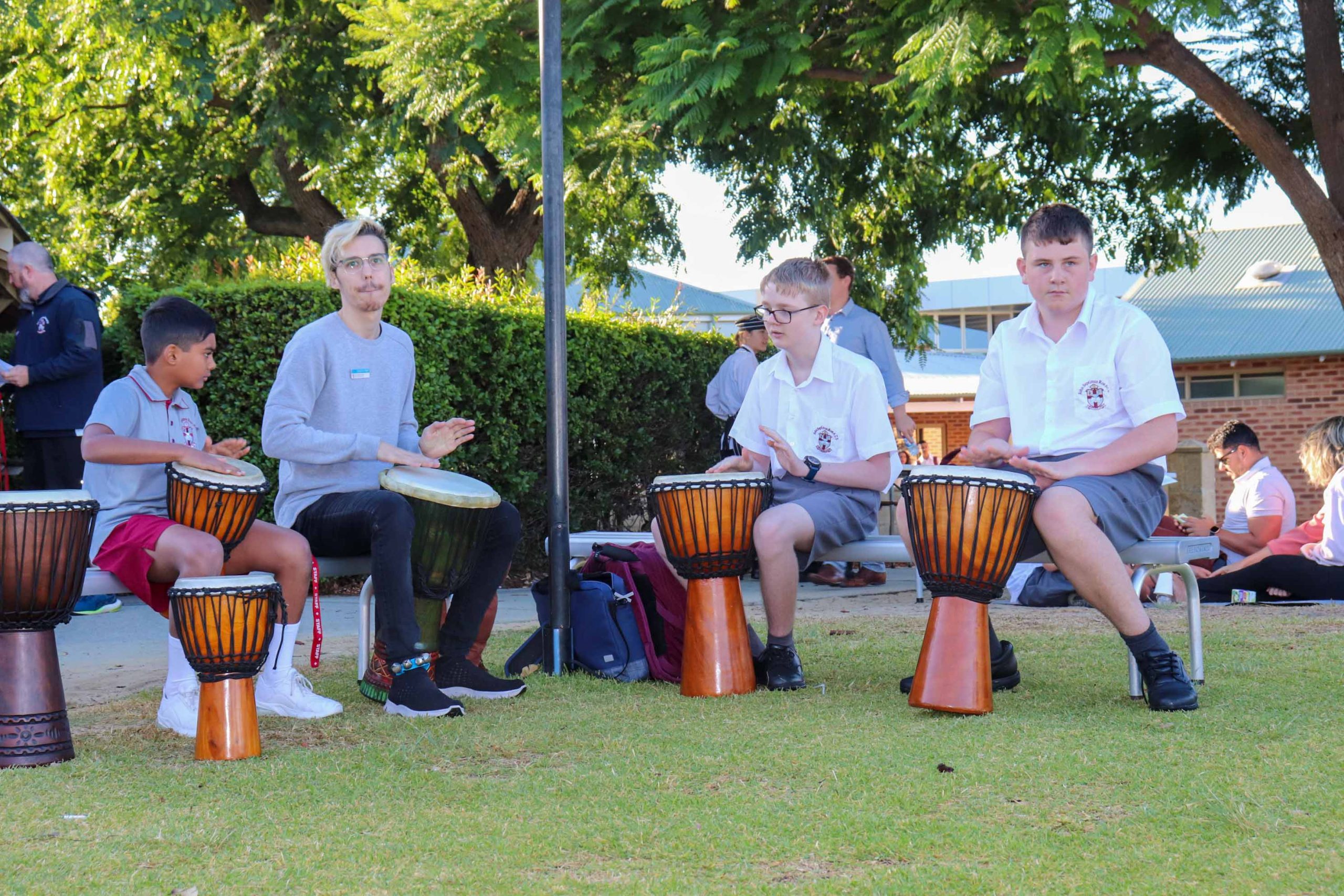Pictured is a man and three boys drumming at The Rite Journey Call and Departure Ceremony.