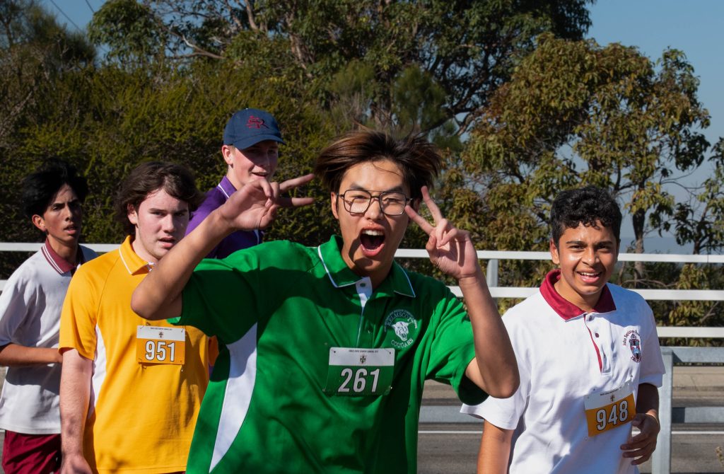 Cross Country students running happy and showing peace sign